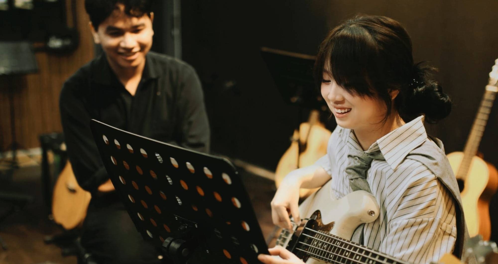 Học viên bass cười tươi trong giờ học, thầy ngồi xem
