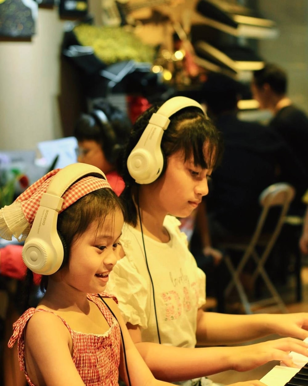 Hai bạn nhỏ đeo tai nghe chơi piano